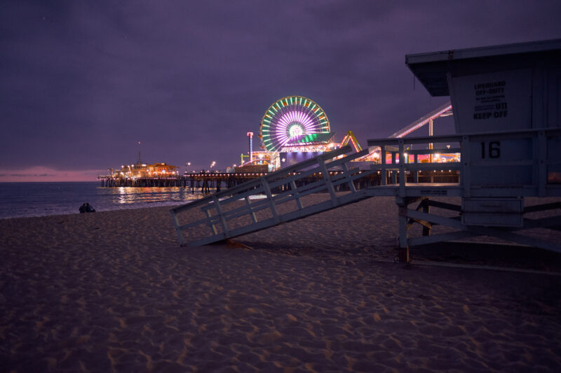 a beach with a pier and a ferris wheel